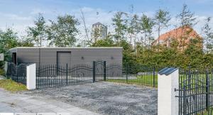 a black fence with a gate in front of a building at patriciervilla i 2plan udlejes in Hjørring