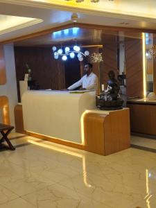 a man standing behind a counter in a lobby at Hotelyashraj in Pipra Dewās