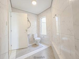 a white bathroom with a toilet and a shower at Wafeh Fleming Suítes Pampulha in Belo Horizonte +22 photos