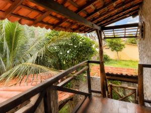 a balcony with a wooden railing and a palm tree at Casa do Parcerito in Cajueiro