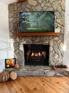 a stone fireplace with a television on top of it at Fehrway to Heaven in Blowing Rock