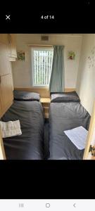 two beds in a small room with a window at Promenade Betty's in Ingoldmells