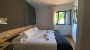 a bedroom with a bed with white sheets and a window at Hotel Cal Tet in L'Estartit