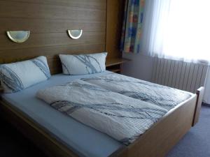 Schlafzimmer mit einem Bett mit einem Kopfteil aus Holz in der Unterkunft Gästehaus Kuen in Längenfeld