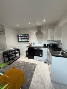 a kitchen with white cabinets and a sink and a table at One Bedroom Luxurious Flat - Free Parking in Rochester