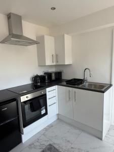 a kitchen with white cabinets and a sink and a stove at One Bedroom Luxurious Flat - Free Parking in Rochester +11 photos