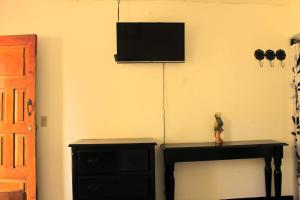 a room with a black dresser and a television on a wall at The Landing Hotel And Restaurant in Moyogalpa