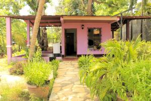 a pink house with a walkway in a garden at The Landing Hotel And Restaurant in Moyogalpa