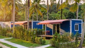 a blue tiny house in the middle of palm trees at Kood Friends Koh Kood in Ko Kood