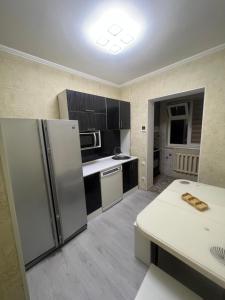 a kitchen with a refrigerator and a table in it at Уют как дома in Shymkent +36 photos