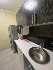 a kitchen with a sink and a refrigerator at Уют как дома in Shymkent
