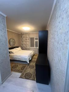 a bedroom with a bed and a table in a room at Уют как дома in Shymkent