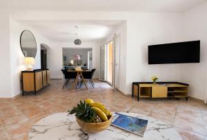 a living room with a television and a table at Villa Bellevue, magnifique vue mer! Piscine chauffée, à10 mns de la plage et du centre! in Cavalaire-sur-Mer
