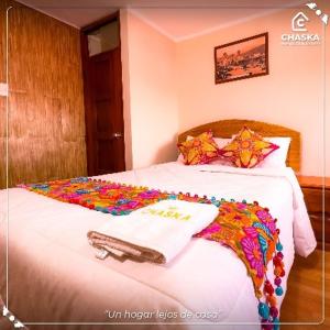 a bedroom with a bed with a white comforter at Chaska Backpackers & Rooms in Ayacucho