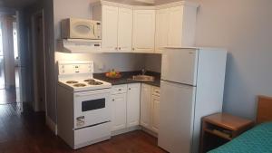 a kitchen with a white stove and a refrigerator at Claymore Inn and Suites in Antigonish