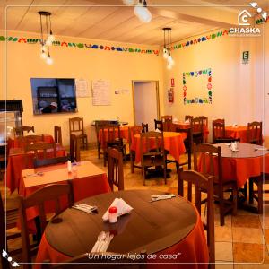 a dining room with tables and chairs with orange table cloth at Chaska Backpackers & Rooms in Ayacucho