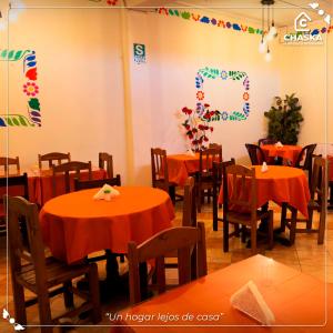 a dining room with tables and chairs with orange table cloth at Chaska Backpackers & Rooms in Ayacucho