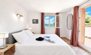 a bedroom with a white bed with a hat on it at Villa Bellevue, magnifique vue mer! Piscine chauffée, à10 mns de la plage et du centre! in Cavalaire-sur-Mer +48 photos
