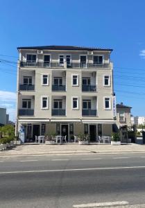 a tall building with tables and chairs in front of a street at Hotel del Mar in Shëngjin