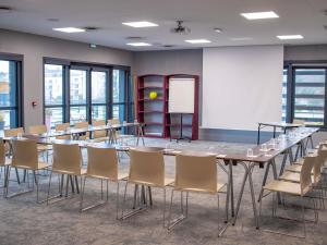 a conference room with tables and chairs and a whiteboard at ibis Rennes Beaulieu in Cesson-Sévigné