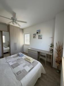a white bedroom with a bed and a desk at Apartman Aloe in Mali Lošinj