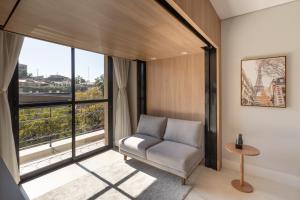 a living room with a chair and a large window at 1986 Apparts in Águas de São Pedro