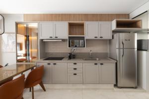 a kitchen with white cabinets and a stainless steel refrigerator at 1986 Apparts in Águas de São Pedro