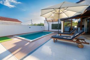 a swimming pool with a chair and an umbrella at Holiday house "Maria" in Privlaka