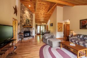 a living room with a large television and a fireplace at High Road Cabin in Banner Elk