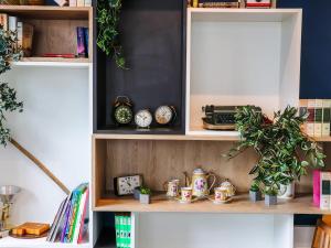 a book shelf with clocks and plants on it at ibis Calais Car Ferry in Calais