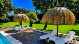 a group of chairs and umbrellas next to a pool at Villa mis Raices in Castilblanco de los Arroyos
