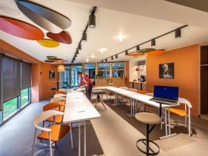 a classroom with tables and chairs and a laptop at IBIS STYLES Rouen Parc Expos Zenith in Saint-Étienne-du-Rouvray