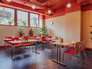 a restaurant with wooden tables and red chairs at Ibis Wien Mariahilf in Vienna