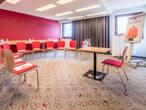 a meeting room with red chairs and a podium at Ibis Wien Mariahilf in Vienna