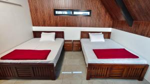 two beds in a small room with red sheets at Vaango Cottages in Idukki