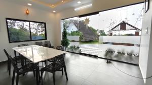 a dining room with a table and chairs and a large window at Vaango Cottages in Idukki
