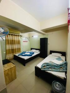 two beds in a room with twoperate beds at Hotel Al Fahad in Dhaka
