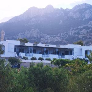 Ein weißes Gebäude vor einem Berg im Hintergrund in der Unterkunft WHITE CASTLE Studios in Lefkos Karpathos