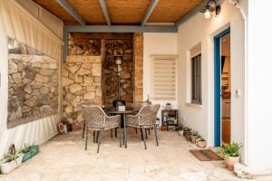 a patio with a table and chairs and a stone wall at המקום של נטע in Mitzpe Hila