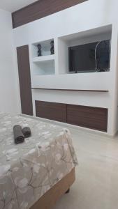 a bedroom with a tv and a bed with slippers at Erminia Apartaments in Vico Equense