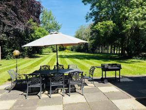 a table and chairs with an umbrella in the grass at Royal Windsor Country Estate Private 5 Acres of Gardens in Windsor