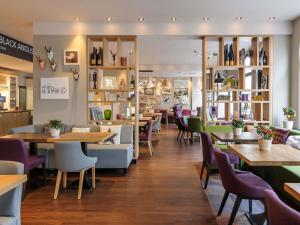 a restaurant with tables and chairs and shelves at Mercure München City Center in Munich