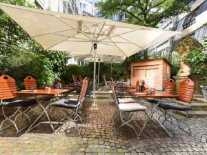 a patio with tables and chairs and an umbrella at Mercure München City Center in Munich