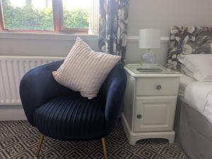 a blue chair with a pillow on it next to a bed at Willowbank House and Lodges in Enniskillen