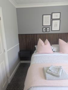 a bedroom with two beds with pink pillows at Willowbank House and Lodges in Enniskillen