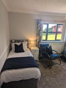 a bedroom with a bed and a chair and a window at Willowbank House and Lodges in Enniskillen