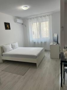 a white bedroom with a bed and a desk at Apartment complex in Roşu