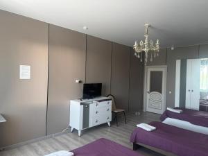 a bedroom with two beds and a desk with a television at Dan plus in Aktobe