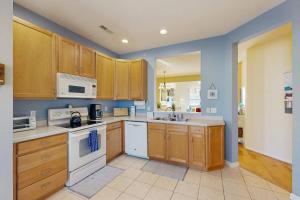 a large kitchen with wooden cabinets and white appliances at Bear Trap Dunes - 214H October Glory Ave in Ocean View +40 photos