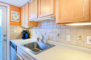 a kitchen with a sink and wooden cabinets at Sunspot Condo --- 2 McKinley Ave, Unit 103 in Dewey Beach